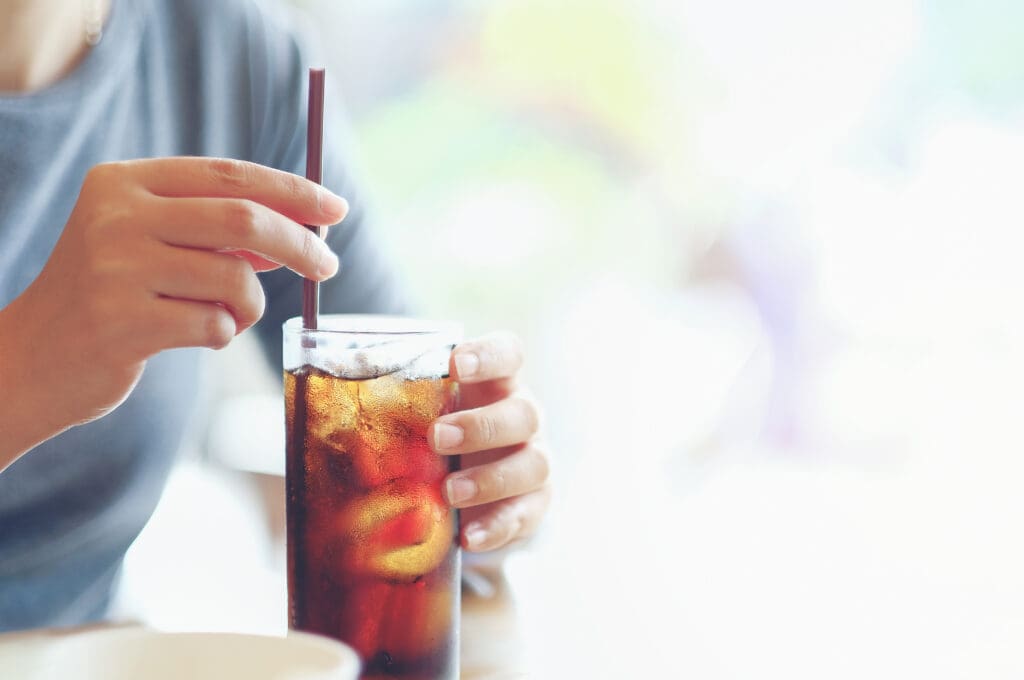 closeup woman Hand holding glass of cola drink in restaurant background, Woman hand glass soft drinks with ice